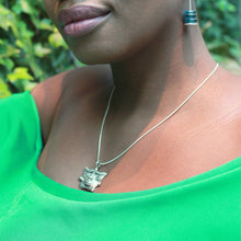 Load image into Gallery viewer, Woman in a green blouse wearing a sterling silver africanmask pendant necklace